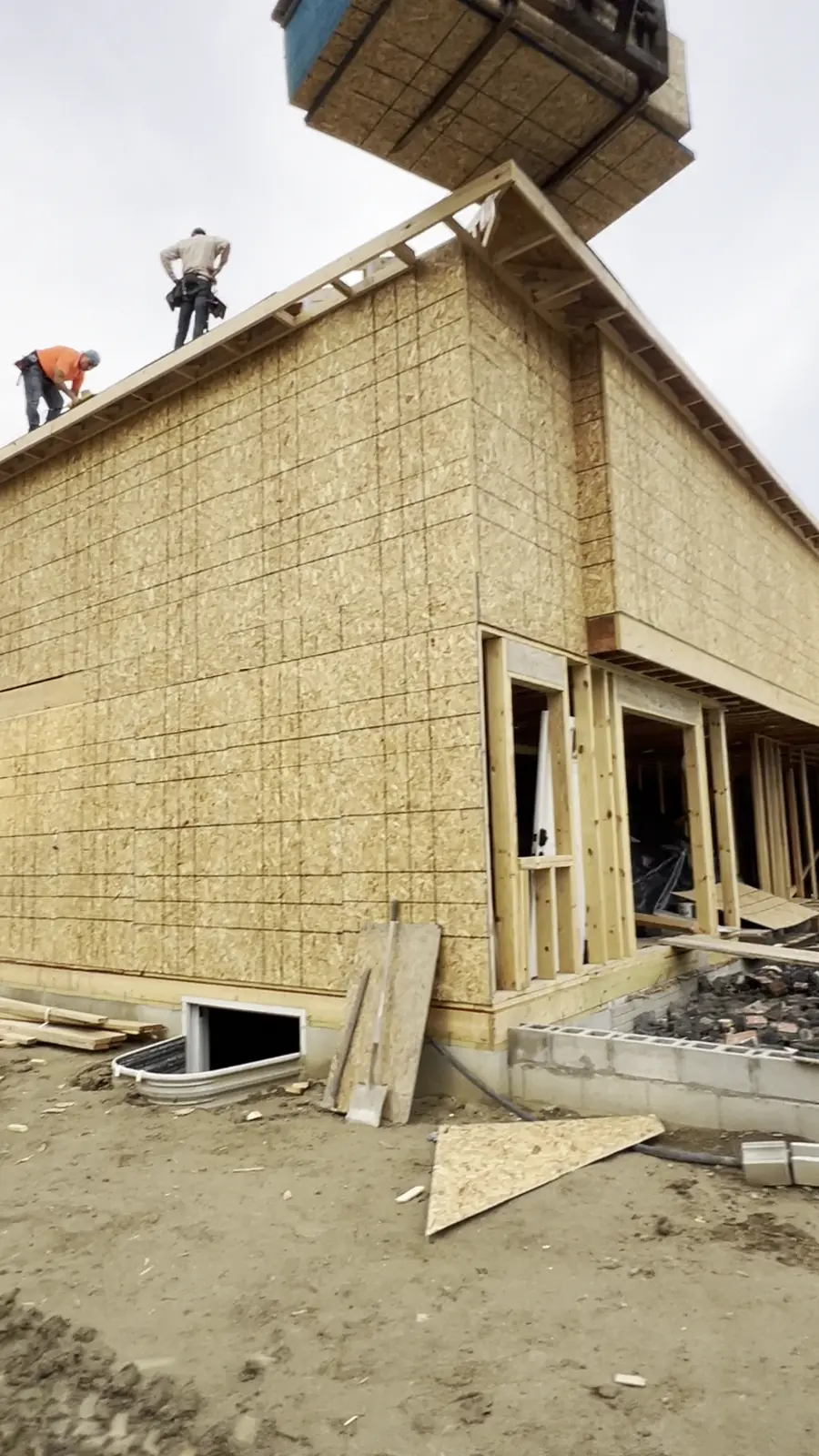 Crew setting roof trusses by crane on a new custom home in Troy MI