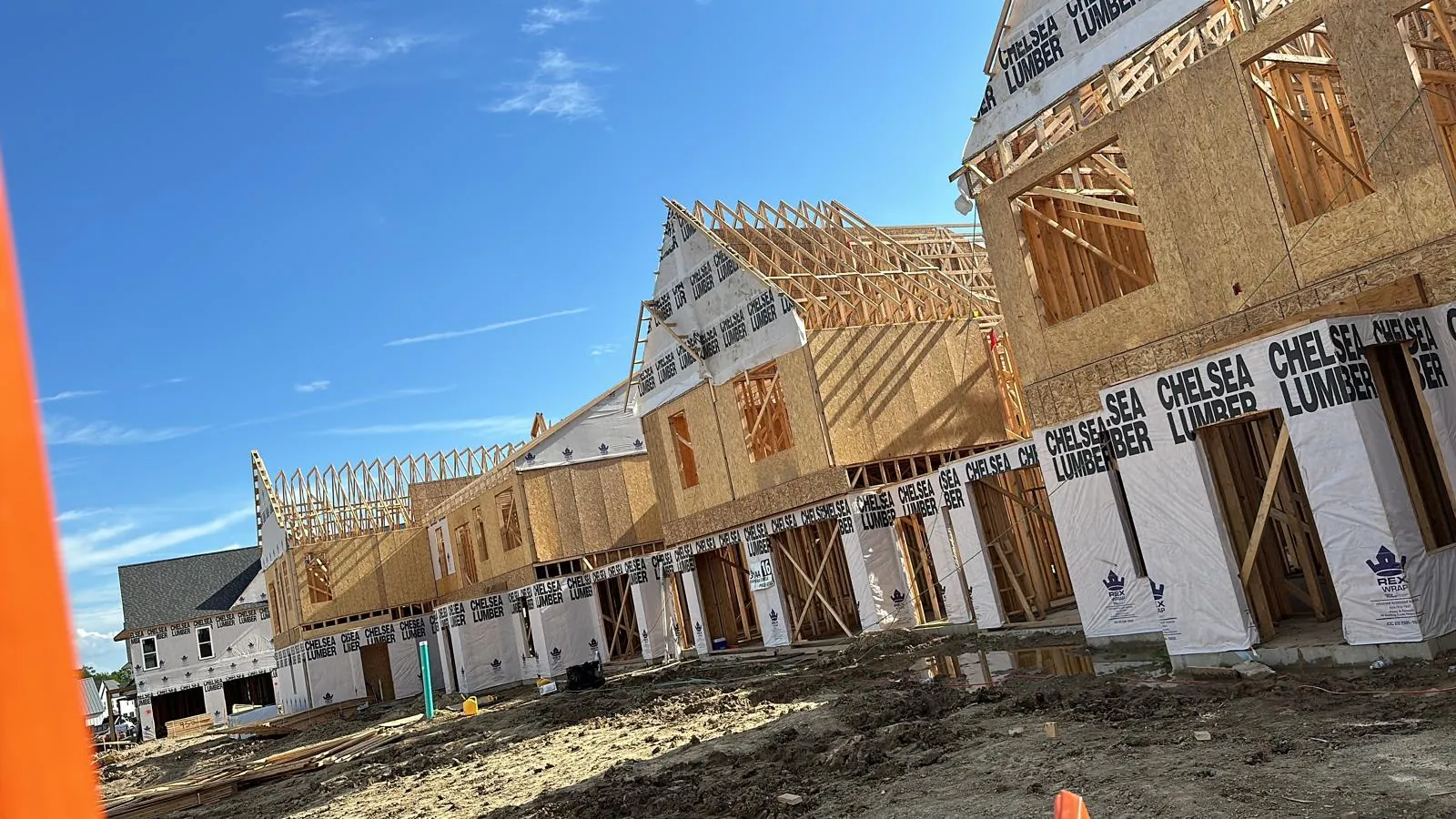 Large multi-unit residential building in rough framing stage, wall and roof framing by Mavericks Construction